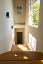 Rustic wooden staircase with large windows that sunlight passes through