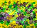 Fun background: many colorful transparent beads swollen in water of the hydrogel lie side by side on a white surface, close, short