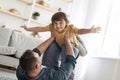 Fun with daddy. Portrait of adorable little boy playing with father at home, man lifting kid up on legs at home Royalty Free Stock Photo