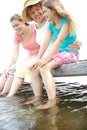 Fun on the deck. A cute young girl sitting on a pier at the lake with her mother and granny. Royalty Free Stock Photo