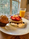 Stack of pancakes with strawberries, blueberries, bananas, and cream with juice and muffin Royalty Free Stock Photo