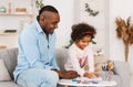 Fun family activities. Senior African American man and his curly granddaughter drawing together at home Royalty Free Stock Photo