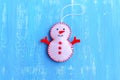 Fun felt Christmas snowman ornament isolated on a blue wooden background. How to make a Christmas snowman ornament. Step