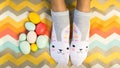 Fun Flat Lay of person wearing bunny socks with Easter eggs. blanket. Copy space