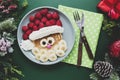 Winter food for kids. Christmas Santa pancake with raspberry and banana for children menu, green background, copy space