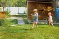 Fun in the garden - boy and girl run around water sprinkler Royalty Free Stock Photo