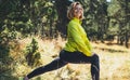 Fun girl exercising outdoors in green forest, activity with stretch legs. Smile fitness woman stretching exercises training Royalty Free Stock Photo