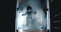 Fun happy creative child in astronaut suit, helmet dancing in dark room with lights, smoke at his space rocket ship.