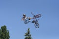 Fun jumping. Young boy, the cycler, soaring high in the blue sky with the bike Royalty Free Stock Photo