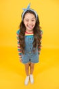 Fun lifestyle little girl long hair denim overalls, cheerful grimace concept Royalty Free Stock Photo