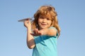 Fun little boy dreams of aviator while playing a paper plane at sky. Imagination, kids freedom. Royalty Free Stock Photo