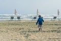 Little boy in a jacket running on the sandy beach at autumn