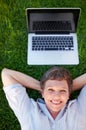 Fun at park. Top view relaxed mature female with laptop smiling while lying on grass.