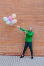 Fun portrait of happy energetic mature businessman holding balloons in street, feeling free, work life balance concept. Royalty Free Stock Photo