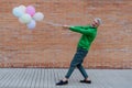 Fun portrait of happy energetic mature businessman holding balloons in street, feeling free, work life balance concept. Royalty Free Stock Photo