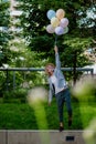 Fun portrait of happy energetic mature businessman holding balloons and walking on wall , feeling free, work life Royalty Free Stock Photo