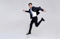 Fun portrait of happy energetic young Asian businessman jumping in mid-air isolated on studio white background
