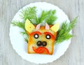 Fun sandwich with slice meat sausage, cheese, bell pepper, olives, dill on plate . funny baby food in the form of an animal face. Royalty Free Stock Photo