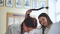 Fun schoolgirls in the classroom. Girl playing with her friend& x27;s pigtail.