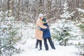 Fun and season concept - Happy mother and son having fun and playing with snow in winter forest