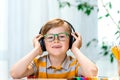 Fun smilling young child enjoying rhythms in listening to music on headphones. Smiling blond boy with freckles in yellow Royalty Free Stock Photo