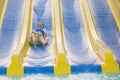 Fun in the sun-pretty girl in bikini comes down water chute in to swimming pool. Beautiful girl riding a water slide. happy woman Royalty Free Stock Photo