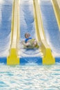 Fun in the sun-pretty girl in bikini comes down water chute in to swimming pool. Beautiful girl riding a water slide. happy woman Royalty Free Stock Photo