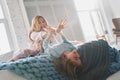 Fun time! Beautiful young mother going crazy with her cute daughter and smiling while sitting on the bed at home Royalty Free Stock Photo