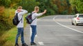 Fun of traveling. Enjoying summer hike. Looking for transport. twins walk along road. stop car with thumb up gesture Royalty Free Stock Photo