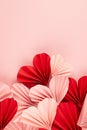 Fun Valentines day festive background in asian style - heap pink and red paper hearts of folded fans on gentle pastel pink color.