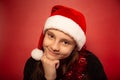 Fun waiting thinking child girl guessing the gift on new year in santa claus hat on red background. Happy Christmas Royalty Free Stock Photo