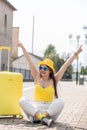 Fun weekend: a young tourist in a bright image is preparing to leave. Stylish vacation: a woman in yellow clothes and Royalty Free Stock Photo