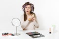 Fun woman with curlers using combing with comb her hair, sitting at table applying makeup with set facial decorative Royalty Free Stock Photo