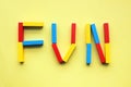 Fun, word laid with colored wooden blocks on yellow background