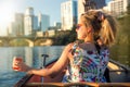 Fun young woman in sunglasses smiling,  enjoying life and having fun in boat on a river next to a city skyline Royalty Free Stock Photo