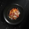 Funchoza with beef and vegetables on a black background, top view, copy space. Glass noodles, Asian food. Royalty Free Stock Photo