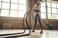 Functional training. Young athletic woman with perfect body doing crossfit exercises with a rope in the gym. Royalty Free Stock Photo