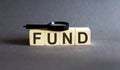 FUND Word block fine and magnifying glass on the gray background. Income, expenses, tax, financial data