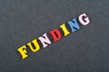 FUNDING word on black board background composed from colorful abc alphabet block wooden letters, copy space for ad text. Learning
