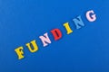 FUNDING word on blue background composed from colorful abc alphabet block wooden letters, copy space for ad text. Learning english