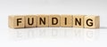 FUNDING word written on wooden cube blocks on white glossy background