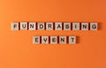 Fundrasing event word phrase in wooden letters. Motivation and slogan. Orange background