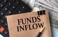 FUNDS INFLOW - words on brown paper on the background of calculator and banknotes