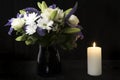 Funeral Bouquet purple White flowers and burning white candle, Sympathy and Condolence Concept on black background with copy space Royalty Free Stock Photo