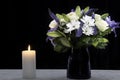 Funeral Bouquet purple White flowers and burning white candle, Sympathy and Condolence Concept on black background with copy space Royalty Free Stock Photo