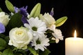 Funeral Bouquet purple White flowers and burning white candle, Sympathy and Condolence Concept on black background with copy space Royalty Free Stock Photo