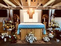 A funeral service is prepared in a church with a cross, flowers, and a flag