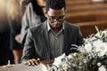 Funeral coffin, death and black man sad, grieving and mourning loss of family, friends or dead loved one. Church service