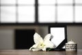 Funeral photo frame with black ribbon, lily and candle on table indoors. Space for design Royalty Free Stock Photo