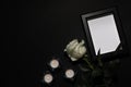 Funeral photo frame with black ribbon, white rose and candles on dark background, flat lay. Space for text Royalty Free Stock Photo